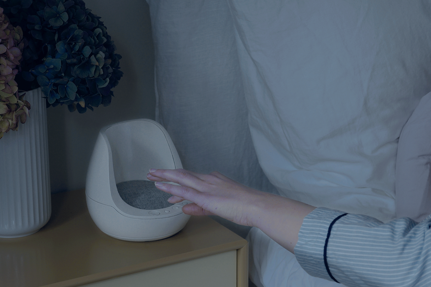 Bildet viser en hånd som skal til å trykke på søvnklokken for å starte en beroligende lydspor.